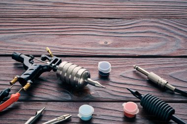 Dövme makinesi, aletler ve malzemeler ahşap arka planda. Dövme stüdyosu.