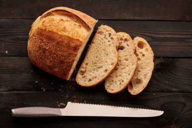 Koyu ahşap masada taze pişmiş ev yapımı tartin ekmeği.