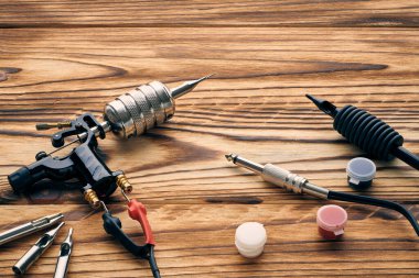 Dövme makinesi, aletler ve malzemeler ahşap arka planda. Dövme stüdyosu.