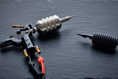 Dövme makinesi, araç gereç ve gereçler siyah tahta üzerine. Dövme stüdyosu.