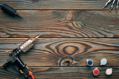 Dövme makinesi, aletler ve malzemeler ahşap arka planda. Dövme stüdyosu.