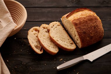 Koyu ahşap masada taze pişmiş ev yapımı tartin ekmeği.