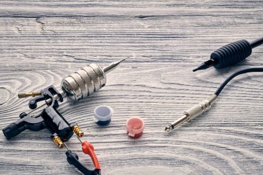 Dövme makinesi, aletler ve malzemeler ahşap arka planda. Dövme stüdyosu.