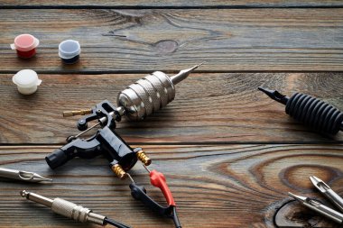 Dövme makinesi, aletler ve malzemeler ahşap arka planda. Dövme stüdyosu.