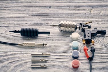 Dövme makinesi, aletler ve malzemeler ahşap arka planda. Dövme stüdyosu.