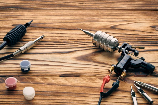 Dövme makinesi, aletler ve malzemeler ahşap arka planda. Dövme stüdyosu.