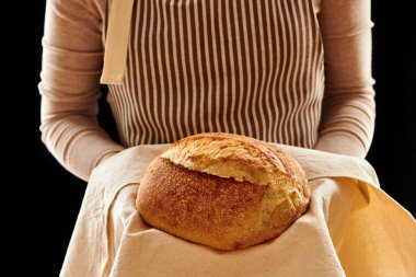 Fırıncı kadın elinde tartinli organik somun ekmeği tutuyor. 