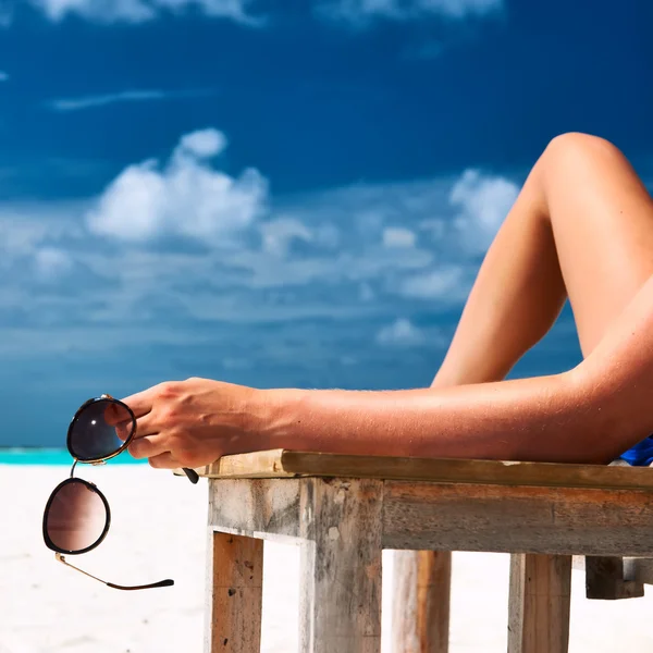Vrouw aan het strand houden zonnebril — Stockfoto
