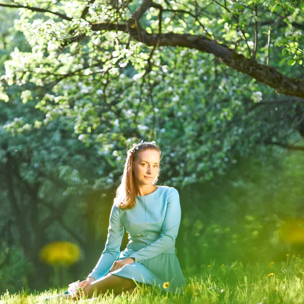 Vrouw in jurk onder appel bloesem — Stockfoto