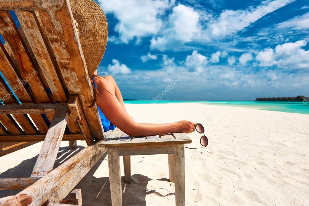 Woman at beach holding sunglasses