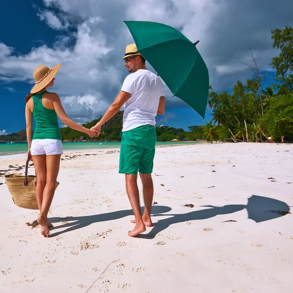 Pareja con sombrilla en la playa tropical —  Fotos de Stock
