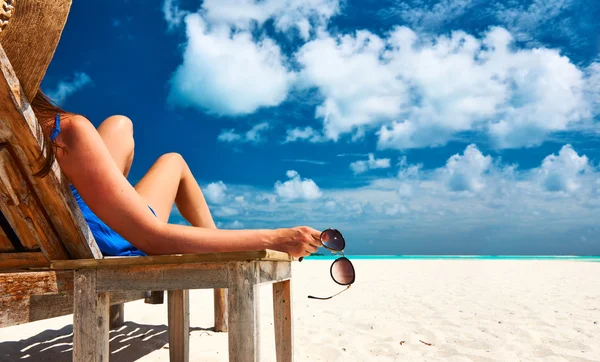 Kobieta na plaży trzymając okulary — Zdjęcie stockowe