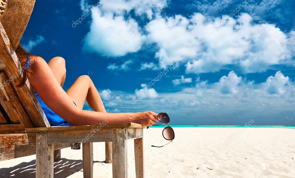Woman at beach holding sunglasses