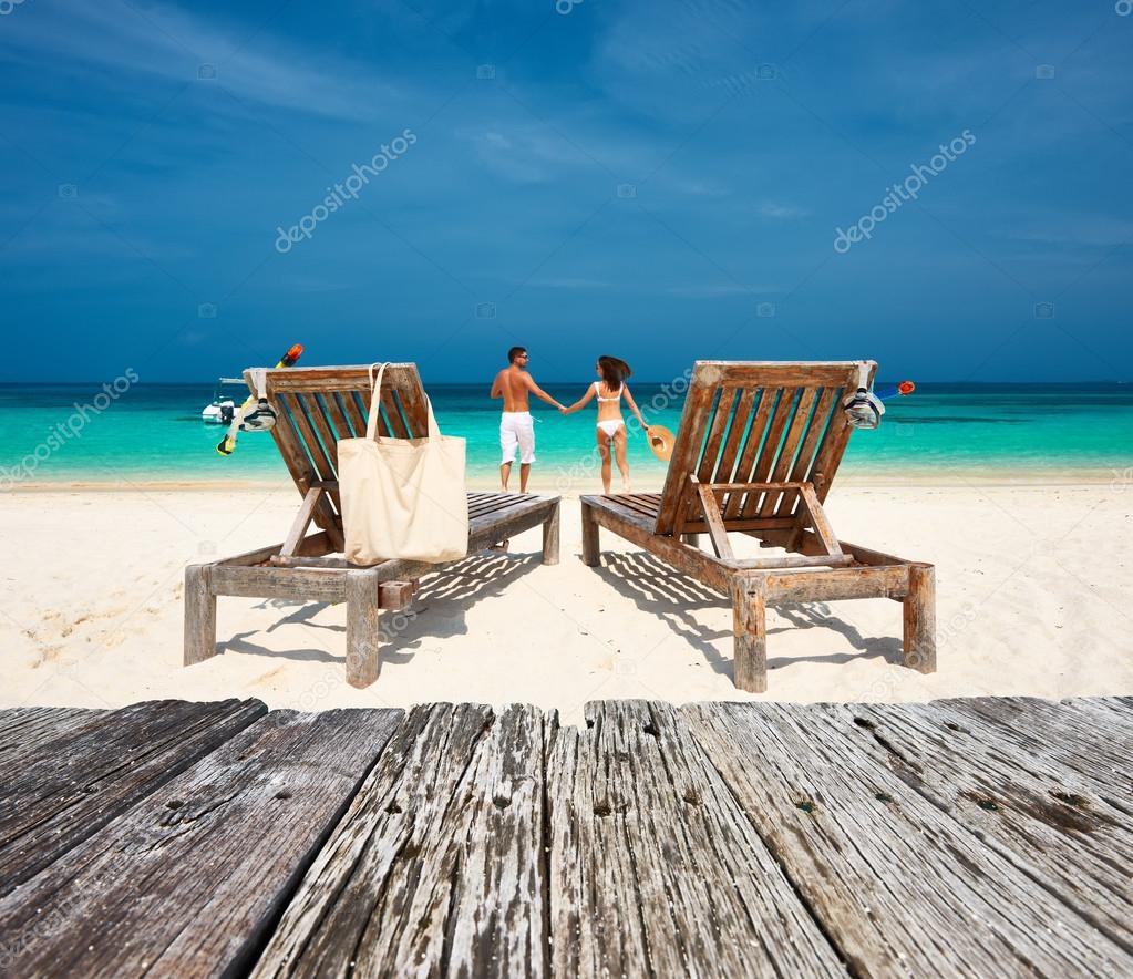 Couple in white relax on beach