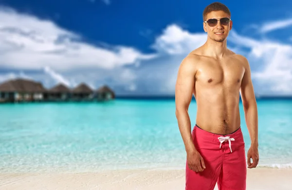 Uomo in spiaggia con bungalow d'acqua — Foto Stock