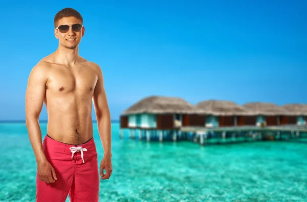 Uomo in spiaggia con bungalow d'acqua — Foto Stock