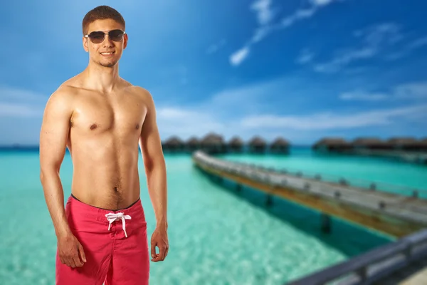 Uomo in spiaggia con bungalow d'acqua — Foto Stock