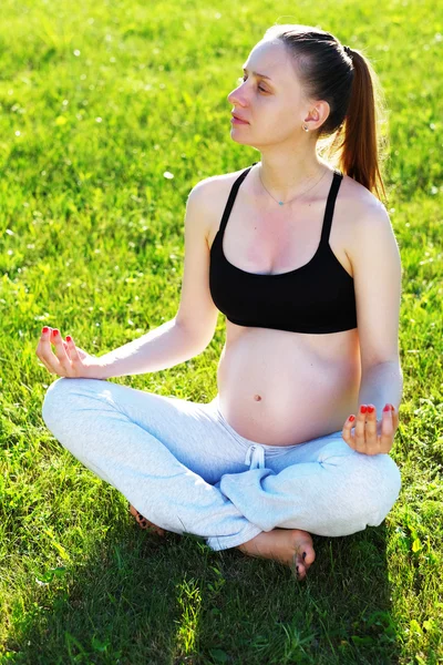 Hamile kadın dışarıda yoga yapıyor. — Stok fotoğraf