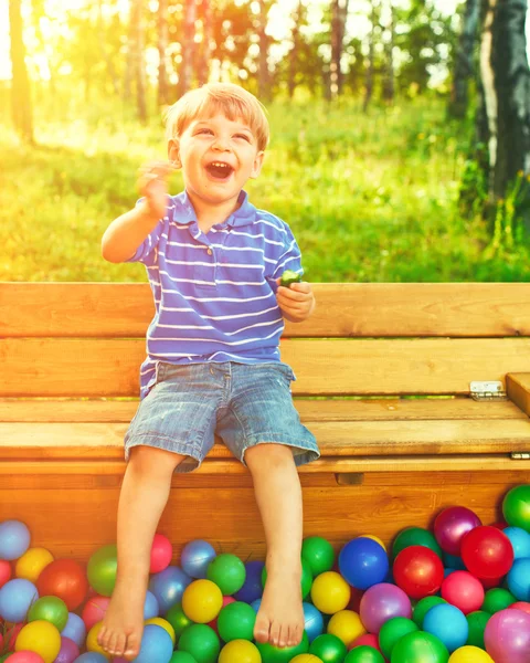 Fröhliches Kind beim Spielen mit bunten Bällen — Stockfoto