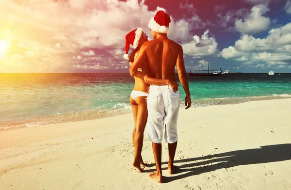 Paar mit Weihnachtsmützen am Strand — Stockfoto