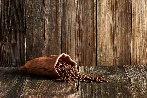 Grãos de café em saco na mesa — Fotografia de Stock