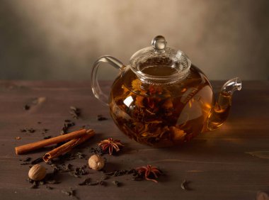 Ahşap bir masada çay ile cam çaydanlık.