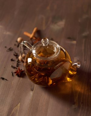 Ahşap bir masada çay ile cam çaydanlık.