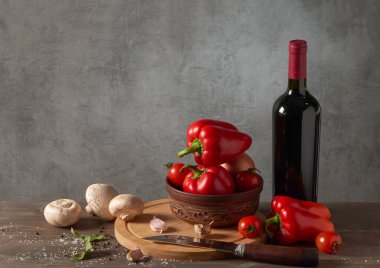Kırmızı biber, şarap, şampiyonlar ve ahşap arka planda kiraz domatesleriyle dolu bir hayat..