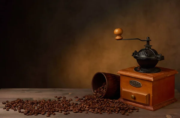 木製のテーブルの上にレトロなコーヒーグラインダーと粘土カップ コーヒー豆が粘土のカップからこぼれた — ストック写真