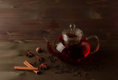 Ahşap bir masada çay ile cam çaydanlık.