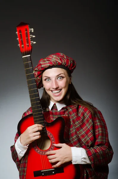 Vrouw in Schotse kleding in muzikaal concept — Stockfoto