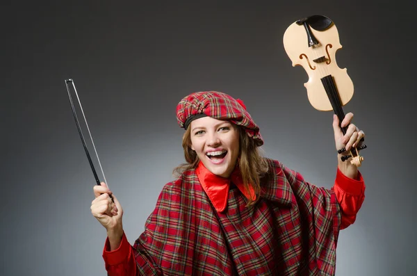 Vrouw in Schotse kleding in muzikaal concept — Stockfoto