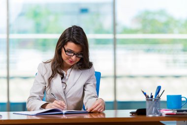 İş kadını büro masasında oturuyor.