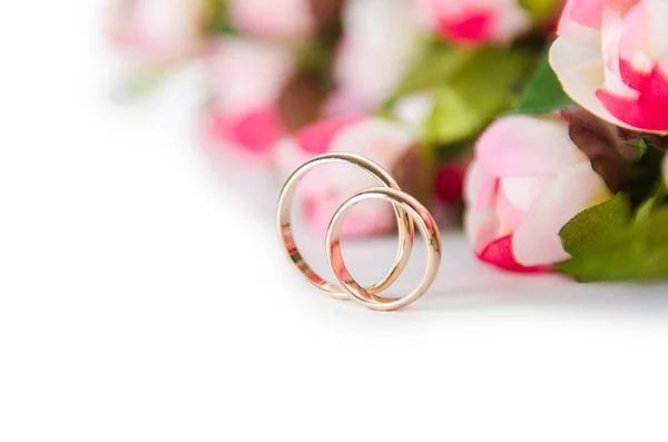 Обручальные кольца и цветы на белом фоне — стоковое фото