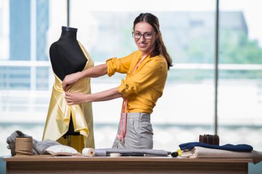 Kadın terzi yeni elbiseler üzerinde çalışıyor.