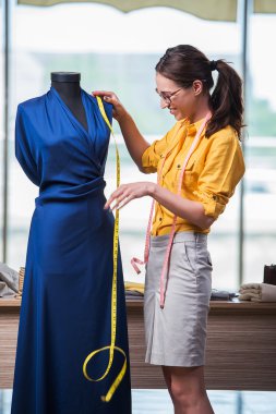 Kadın terzi yeni elbiseler üzerinde çalışıyor.