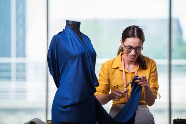 Kadın terzi yeni elbiseler üzerinde çalışıyor.