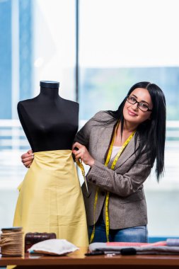 Kadın terzi yeni elbiseler üzerinde çalışıyor.