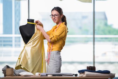 Kadın terzi yeni elbiseler üzerinde çalışıyor.