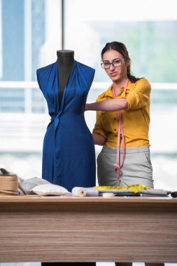 Kadın terzi yeni elbiseler üzerinde çalışıyor.