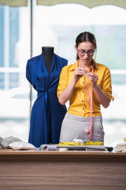 Kadın terzi yeni elbiseler üzerinde çalışıyor.