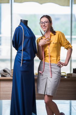 Kadın terzi yeni elbiseler üzerinde çalışıyor.