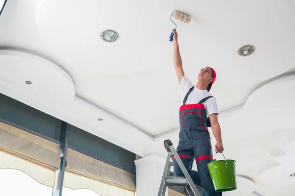 Jeune peintre peignant le plafond dans le concept de construction — Photo