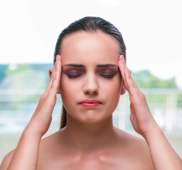 Junge Frau hält ihre Schläfen mit Kopfschmerzen — Stockfoto