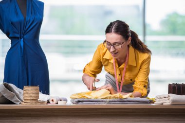 Kadın terzi yeni elbiseler üzerinde çalışıyor.