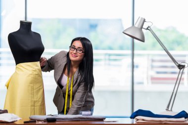 Kadın terzi yeni elbiseler üzerinde çalışıyor.