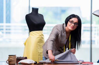 Kadın terzi yeni elbiseler üzerinde çalışıyor.