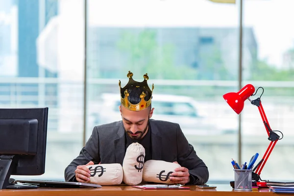 Empresário com coroa e sacos de dinheiro no escritório — Fotografia de Stock