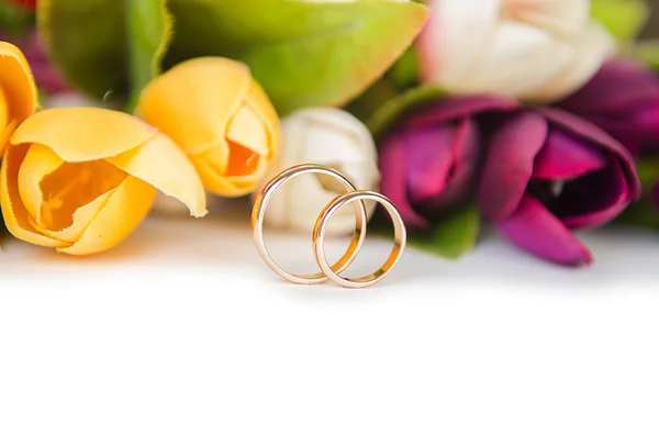 Обручальные кольца и цветы на белом фоне — стоковое фото