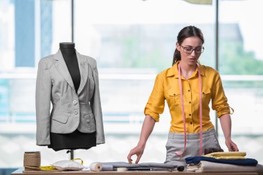 Kadın terzi yeni elbiseler üzerinde çalışıyor.